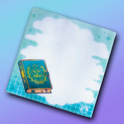 A sticky note pad with a cloudy area for writing, background grids and fading colours, and an illustration of a spellbook.