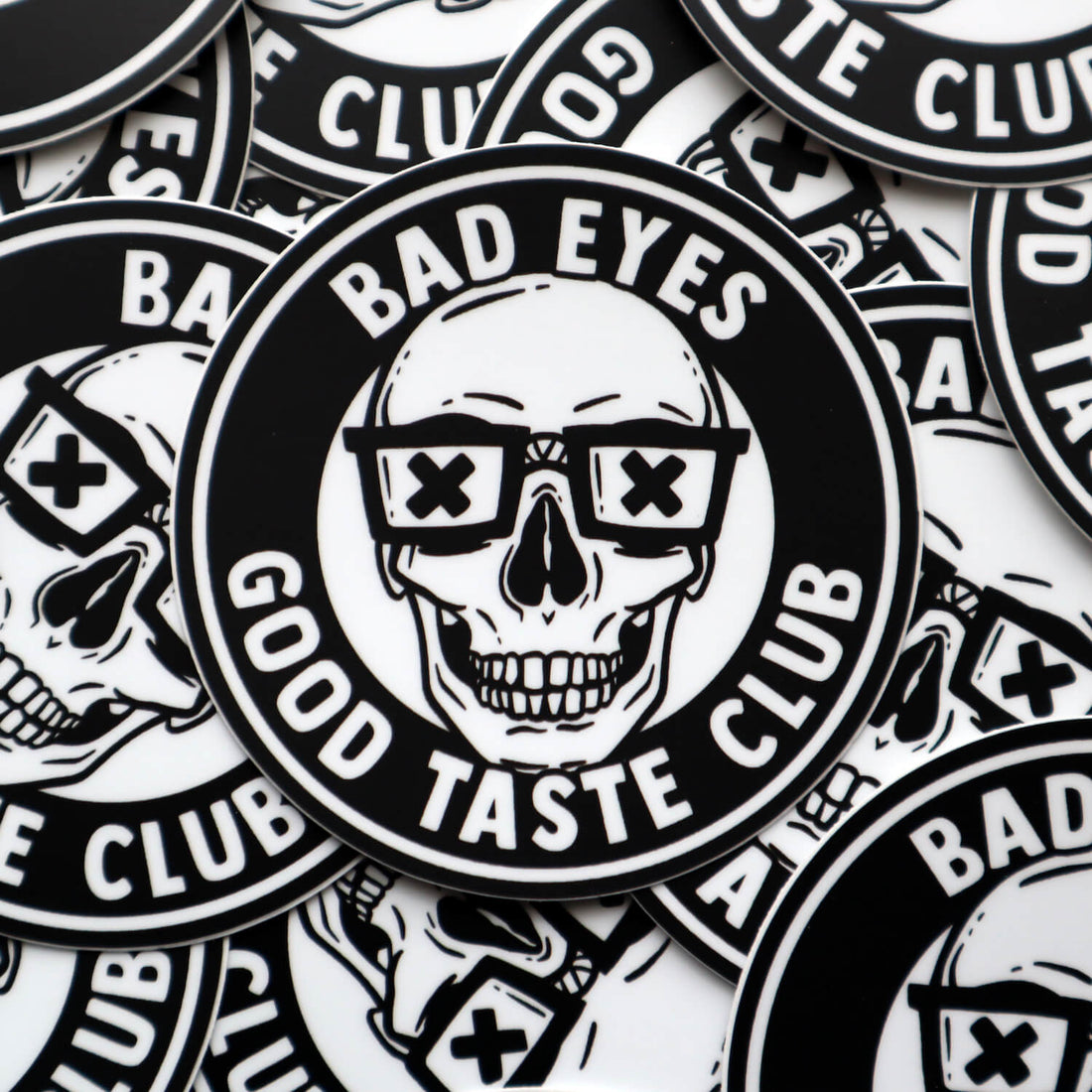 A collection of vinyl stickers featuring a grinning skull wearing nerd glasses and the words Bad Eyes, Good Taste Club.