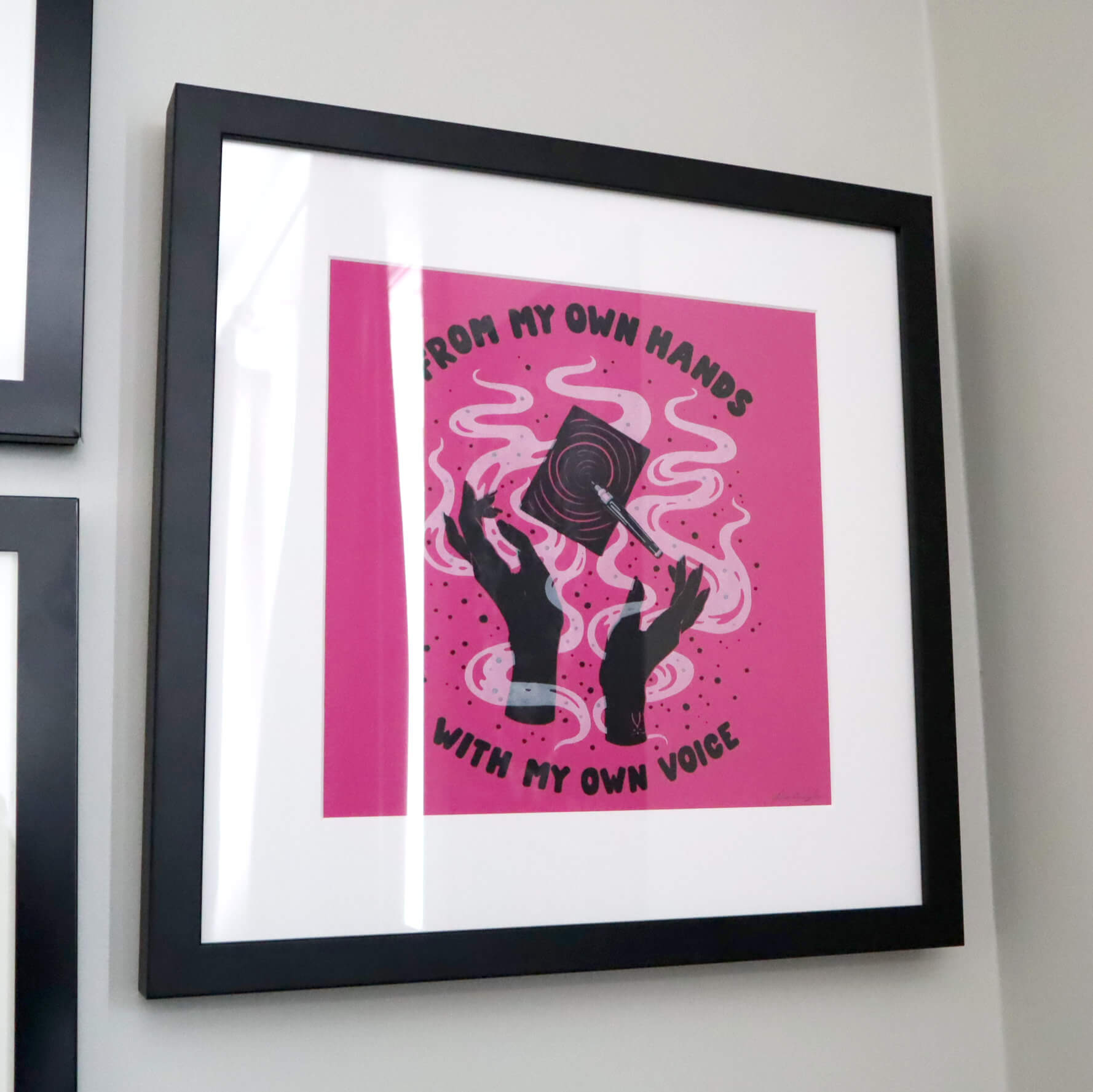 A framed artwork hung on the wall, with the words From My Own Hands, With My Own Voice emblazoned on hot pink paper.