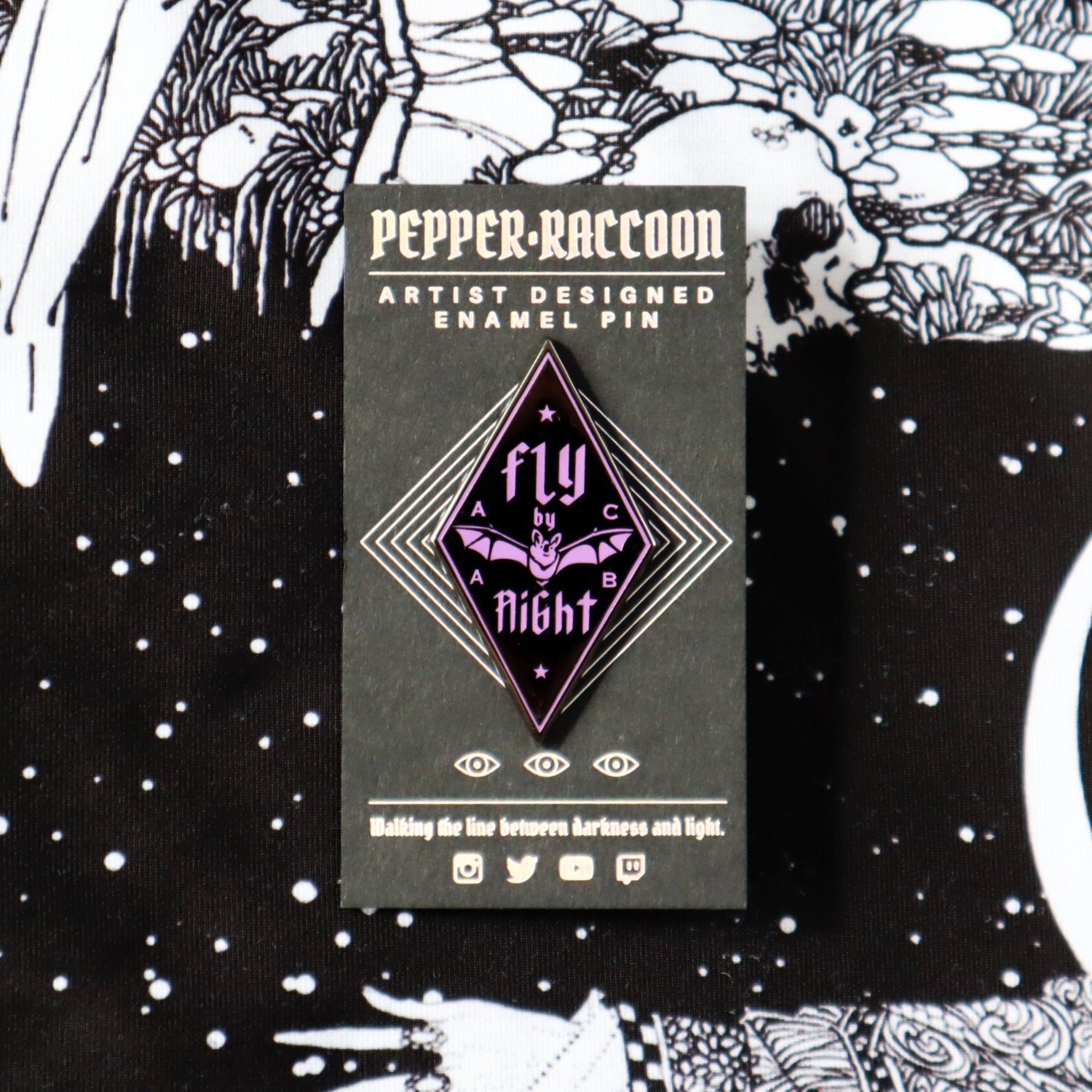 A diamond-shaped, black enamel pin with purple details, it says Fly By Night with a small NZ native bat or pekapeka emblazoned across the centre.